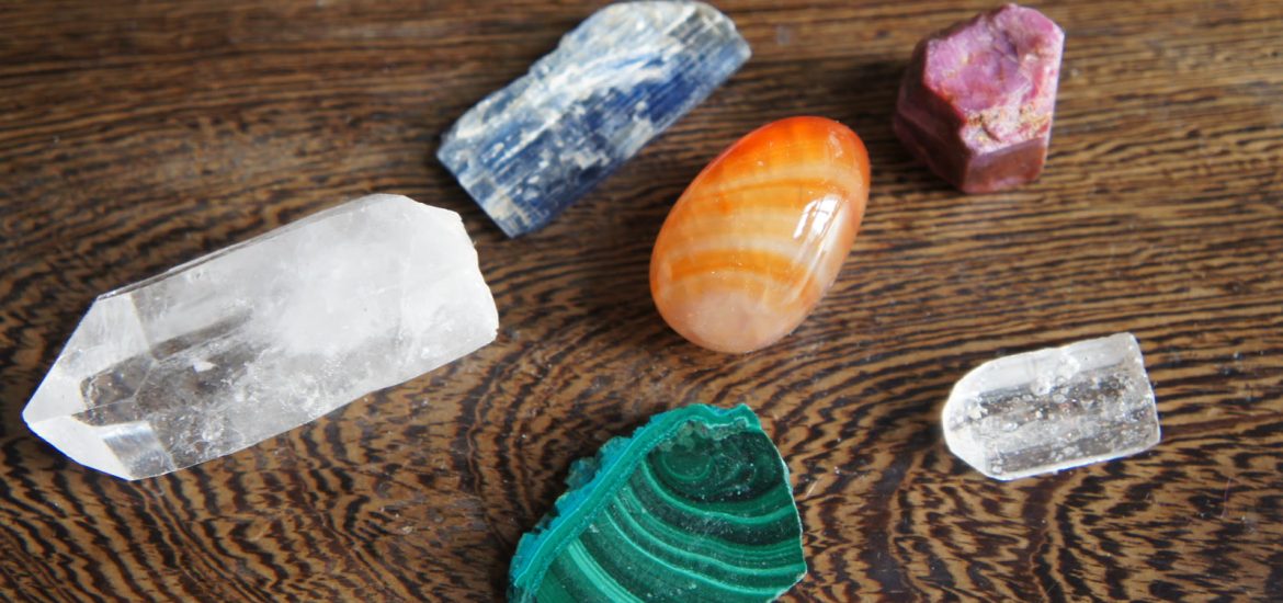 Seks farvede sten side om side: kyanit, rubin, karneol, malakit og to klare kvartser